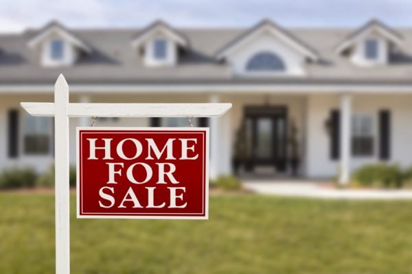 Home For Sale Real Estate Sign in Front of Beautiful New House. Buying a House with Foundation Issues